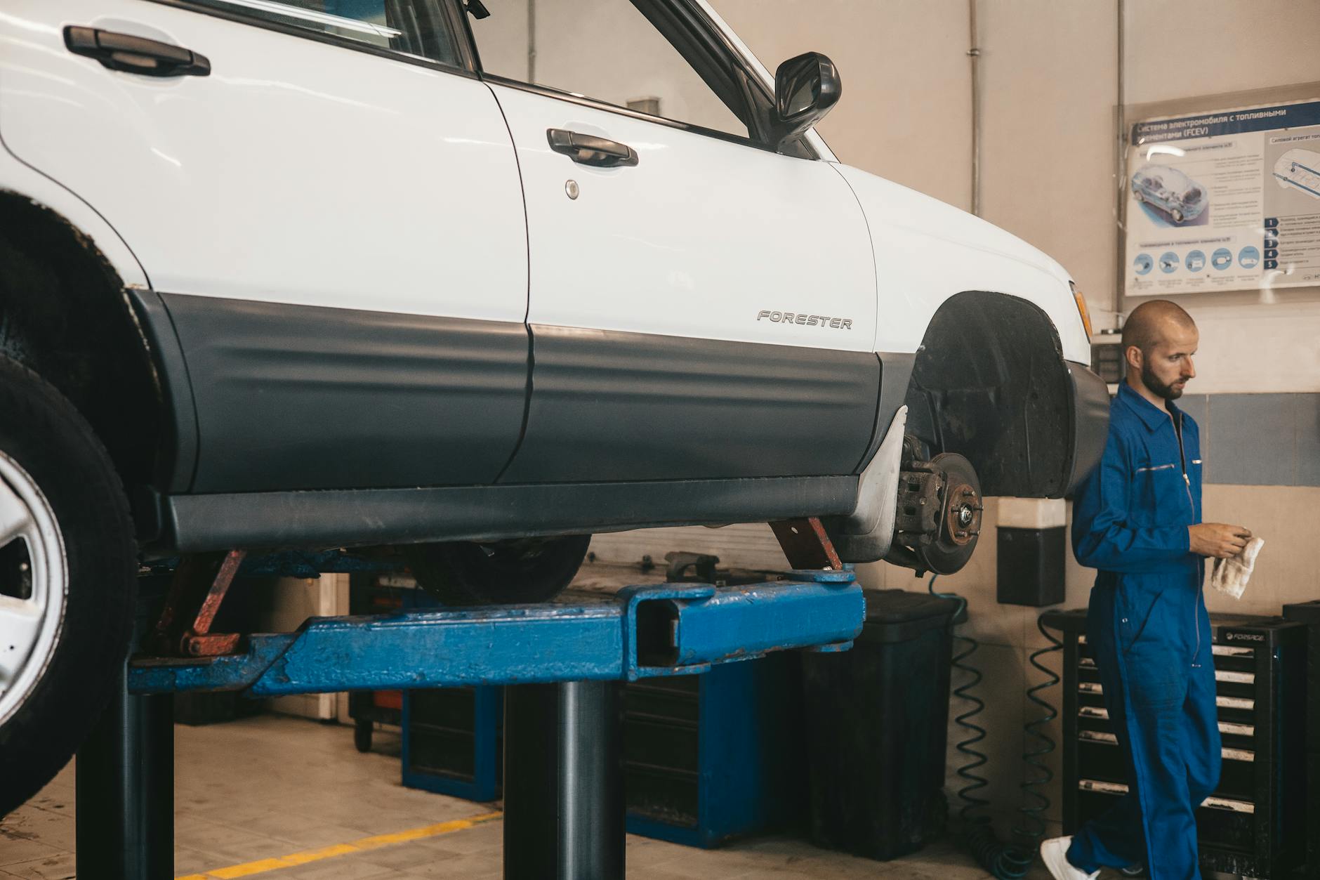 Mechanic evaluating a car on a lift for maintenance in an auto workshop