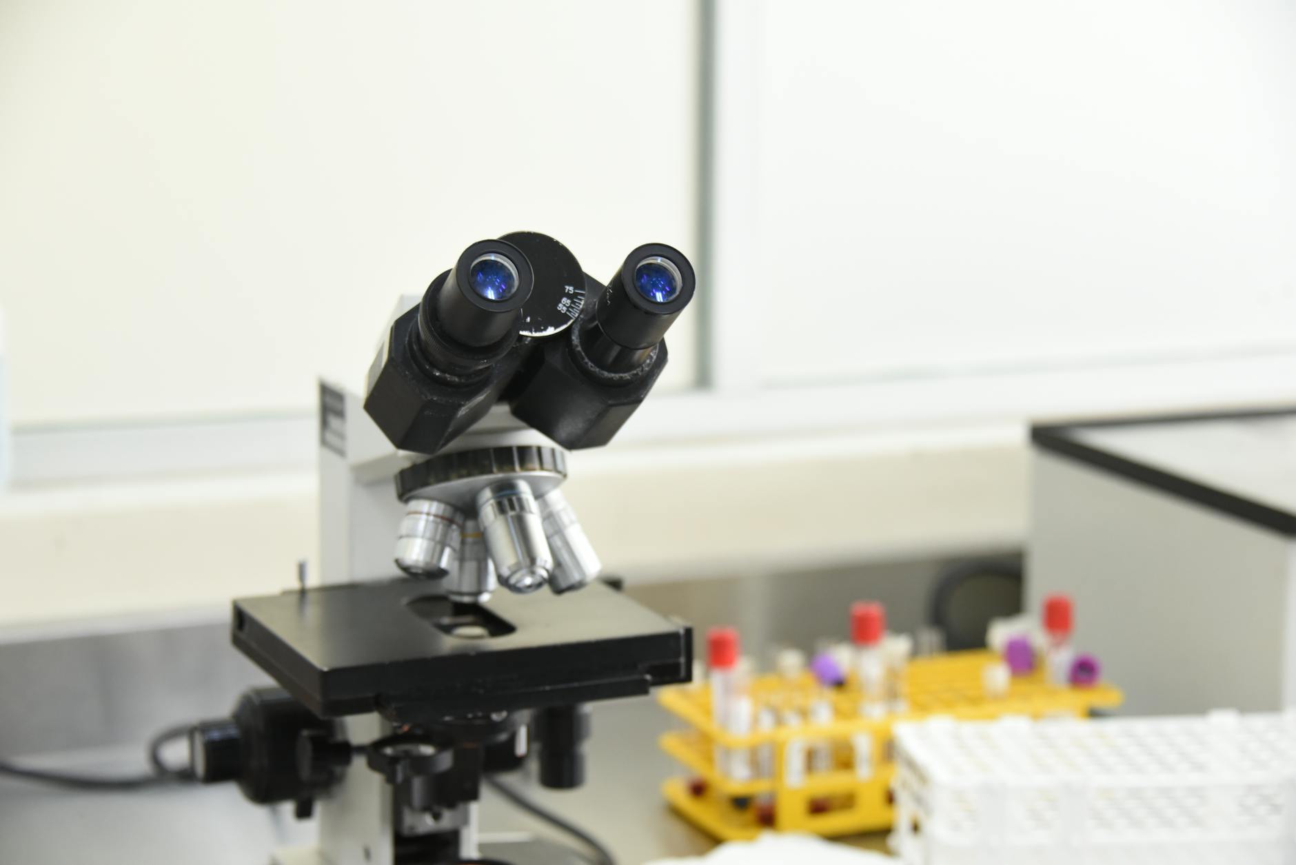 A close-up of a laboratory microscope with test tubes in a scientific research facility.
